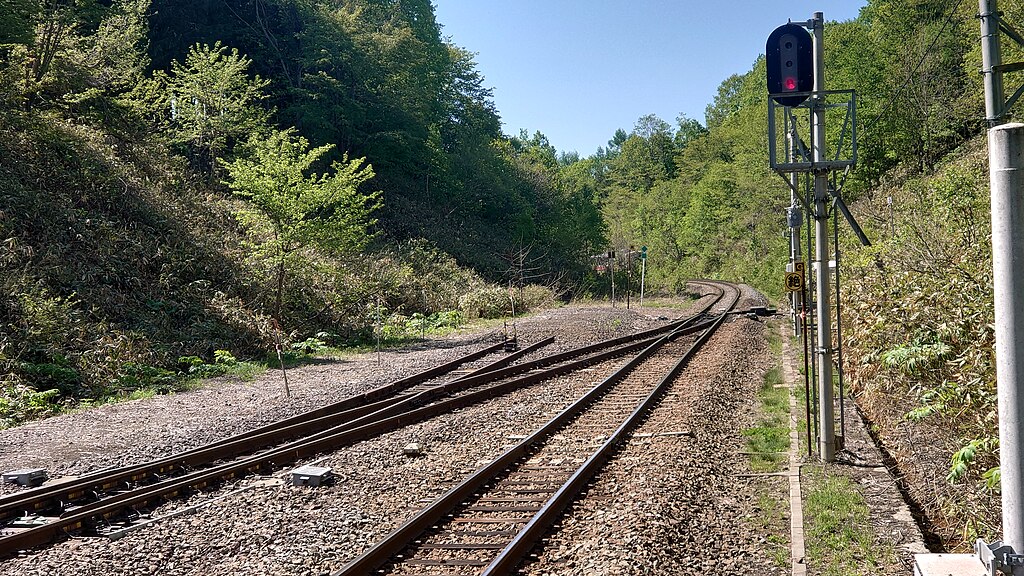 北海道・塩狩峠を走る鉄道の分岐と信号機、緑に囲まれた線路の風景