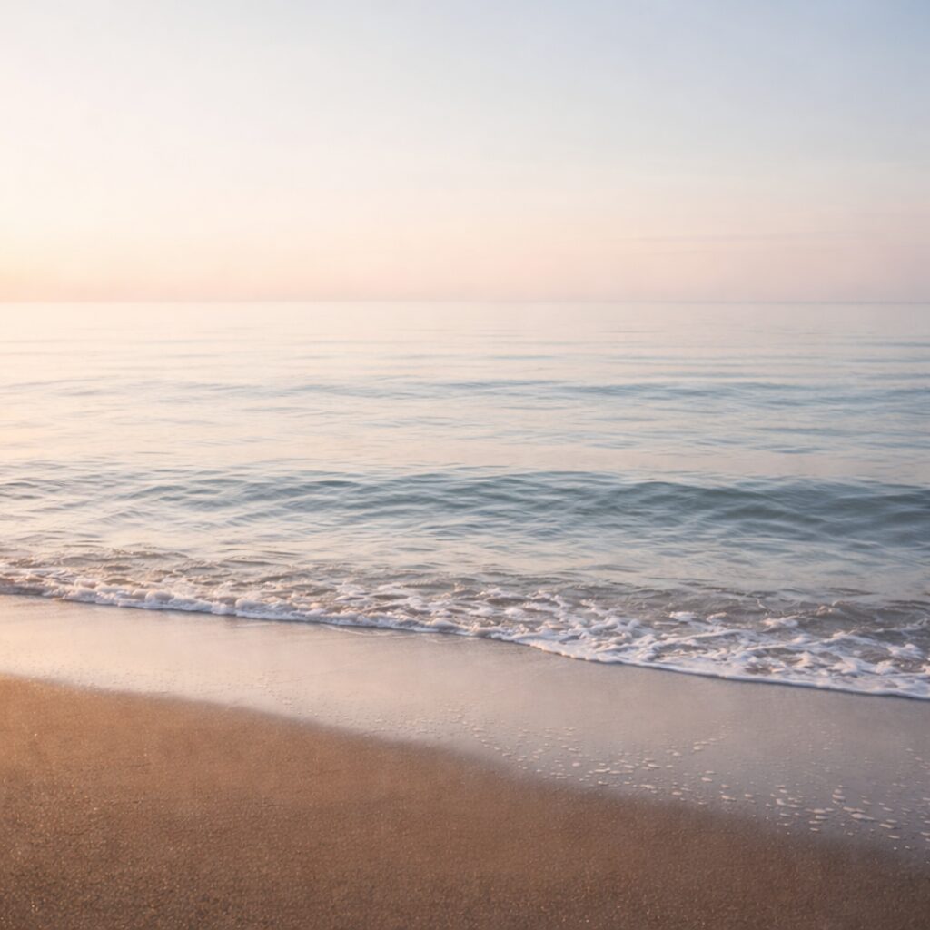 淡い空と水平線、穏やかな小波。朝の光が透明に広がる静かな海